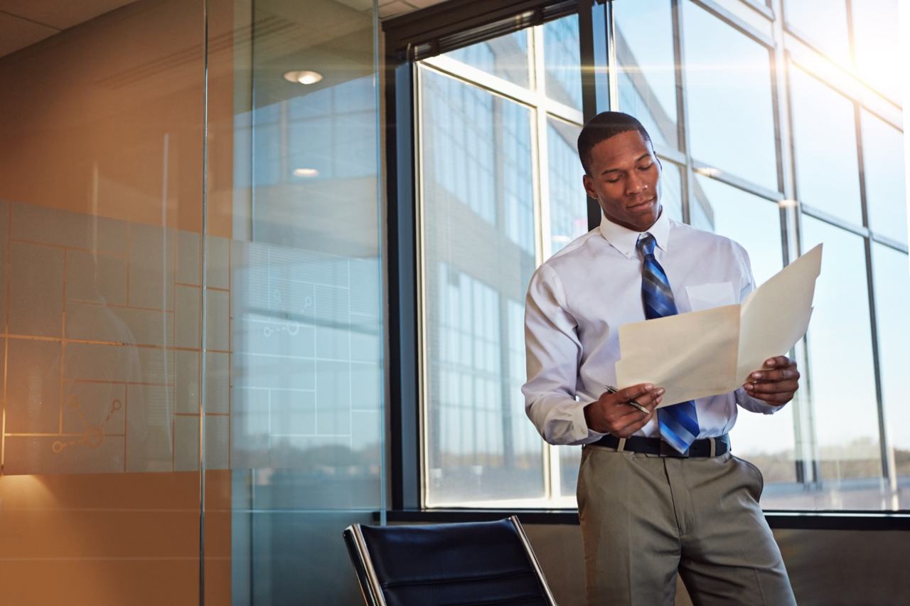 Lawyer reading paperwork near window of law office building Lawyer reading paperwork near window of law office building