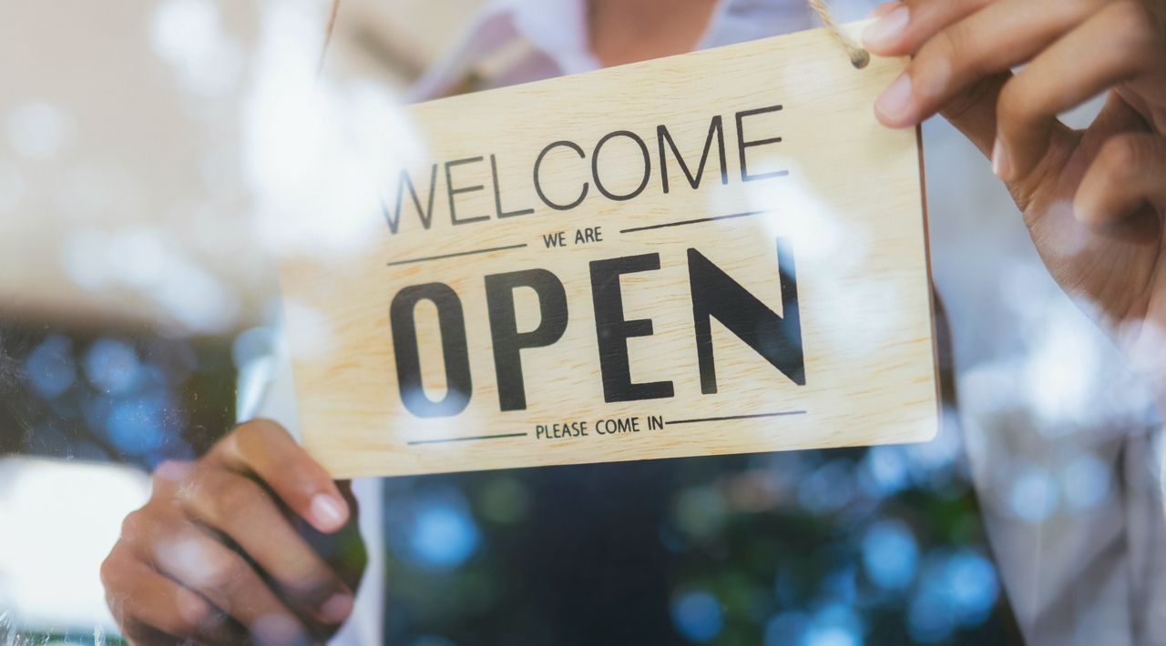 Employee Putting Welcome Sign on Window Employee Putting Welcome Sign on Window